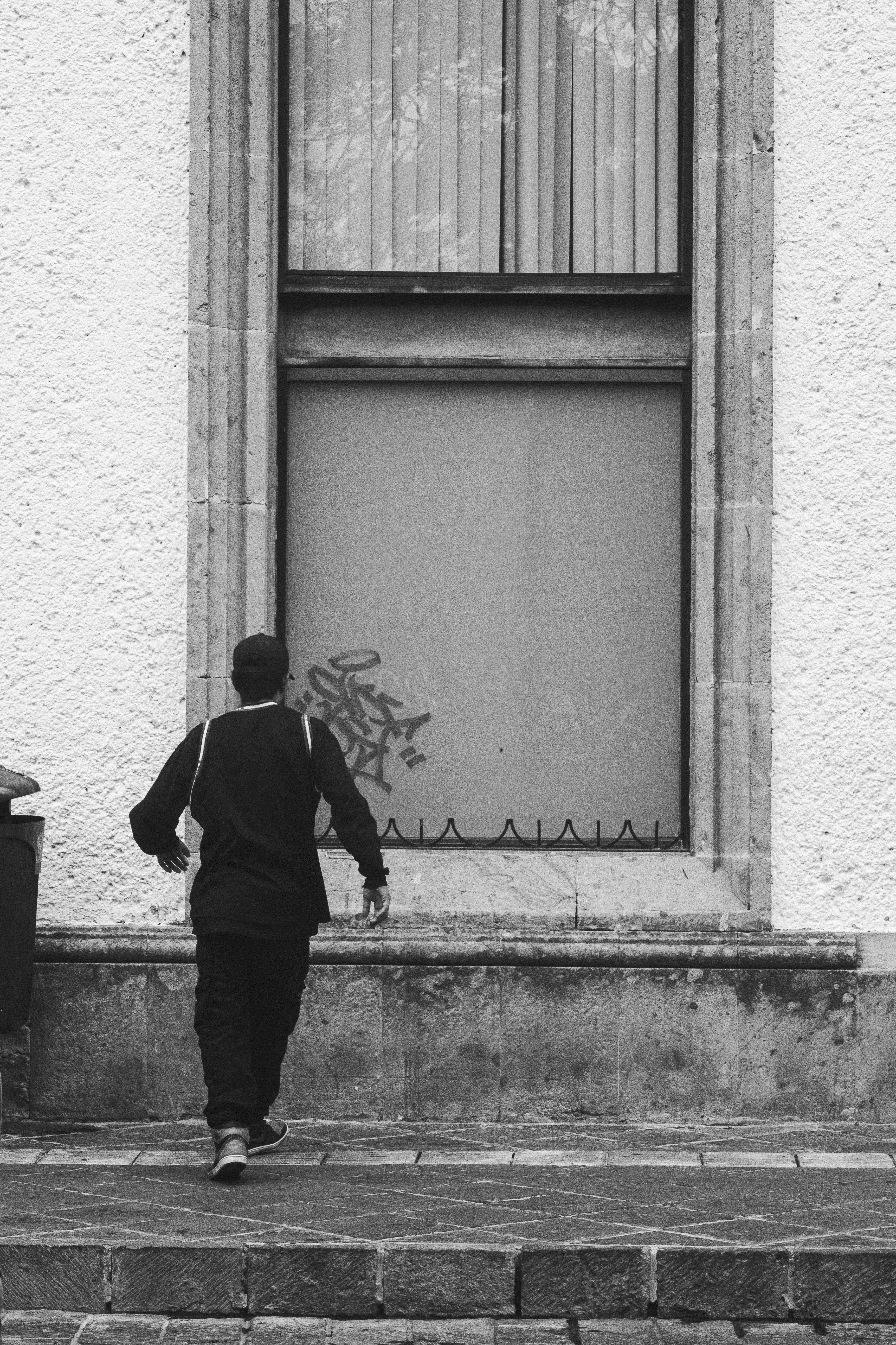 A black and white photo of a man walking down the street